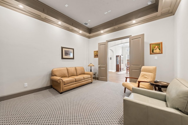 living area featuring visible vents, arched walkways, baseboards, light colored carpet, and ornamental molding