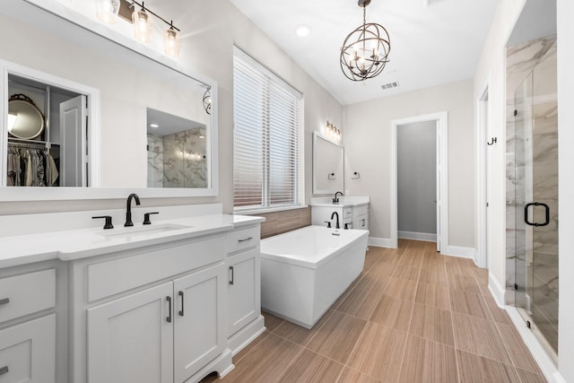 full bathroom with a stall shower, a soaking tub, a sink, and visible vents