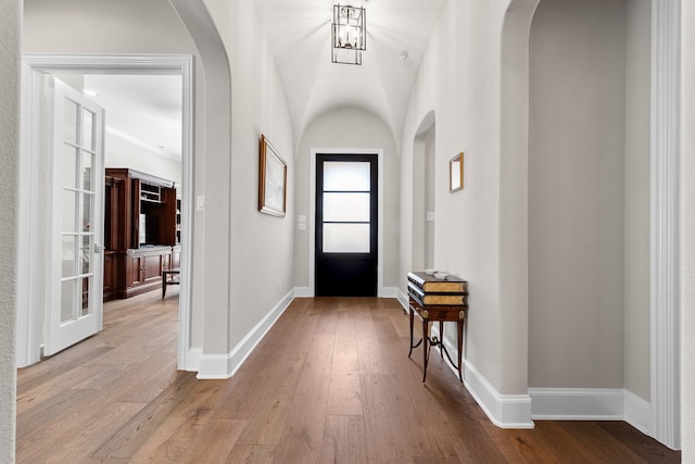 foyer featuring arched walkways, baseboards, and hardwood / wood-style flooring