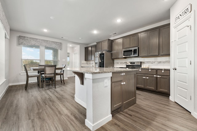 kitchen with stainless steel appliances, dark wood-type flooring, dark brown cabinetry, and backsplash