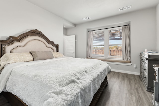 bedroom with visible vents, baseboards, and wood finished floors