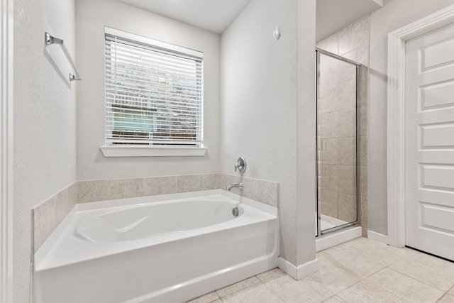 bathroom with baseboards, a stall shower, a bath, and tile patterned floors