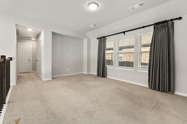 unfurnished room with attic access, visible vents, light carpet, and baseboards