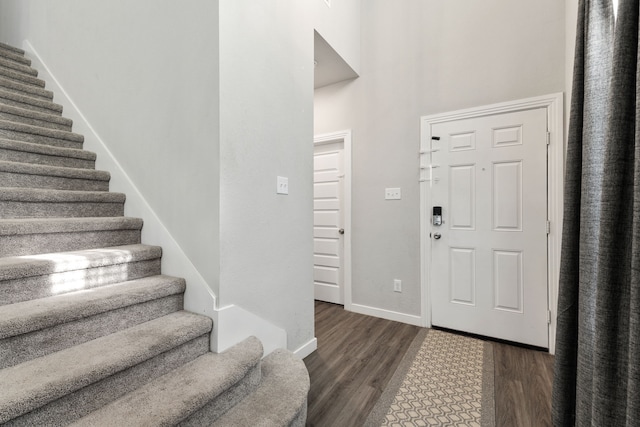 foyer with dark wood-style flooring, stairway, and baseboards