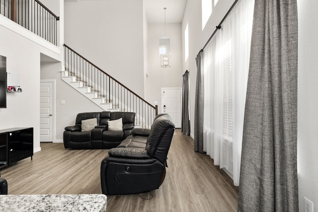 living area with a towering ceiling, stairway, and wood finished floors