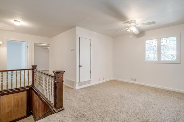 empty room with a ceiling fan, light carpet, visible vents, and baseboards