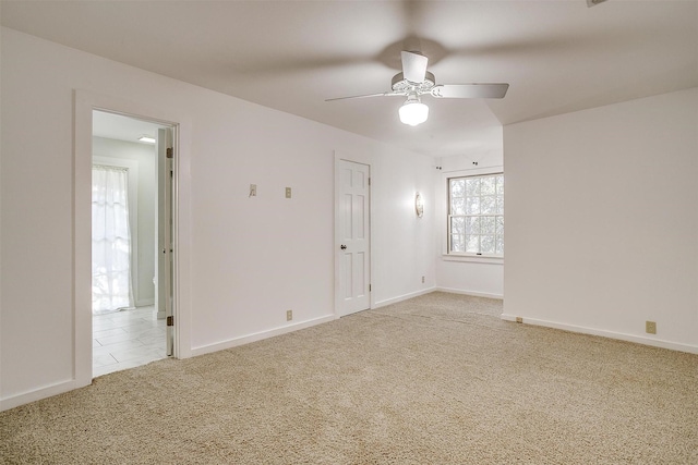 carpeted spare room featuring baseboards and a ceiling fan