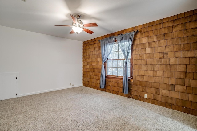 carpeted spare room featuring ceiling fan, built in shelves, and wooden walls