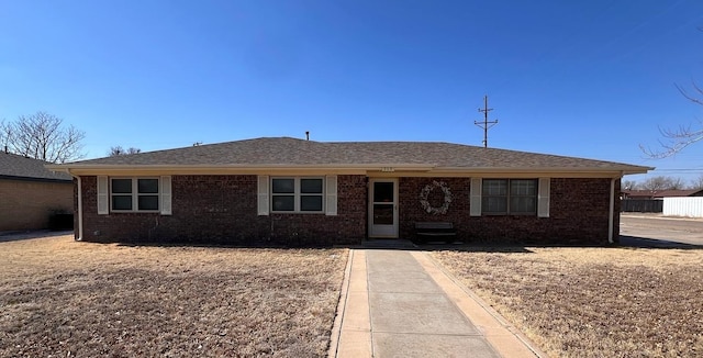 single story home featuring brick siding and a shingled roof