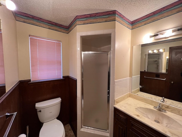 bathroom featuring a stall shower, wainscoting, a textured ceiling, and toilet