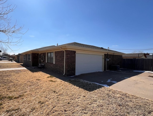 view of front of home featuring a garage, concrete driveway, brick siding, and fence