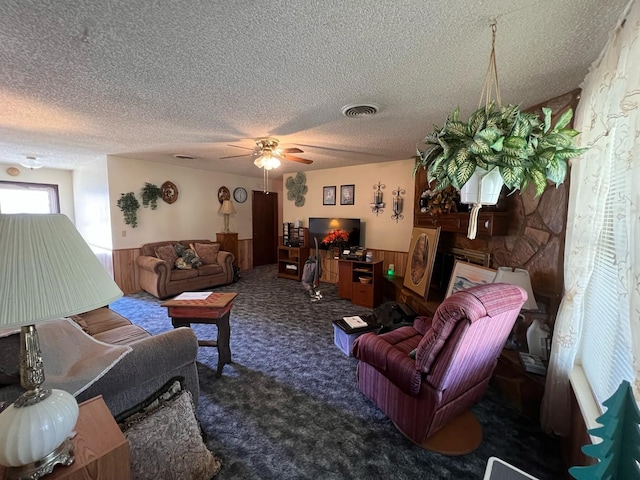 living room with carpet, a wainscoted wall, visible vents, and a textured ceiling