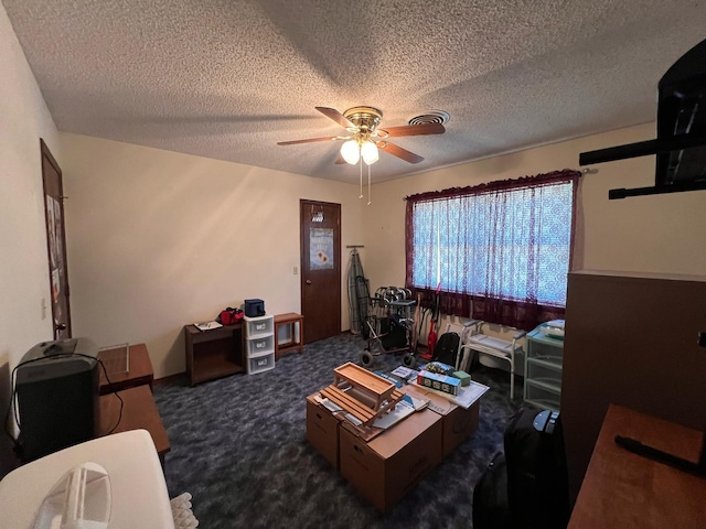 living area with ceiling fan, a textured ceiling, and dark carpet