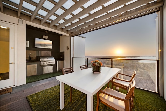 view of patio with outdoor dining space, a grill, exterior kitchen, and a water view