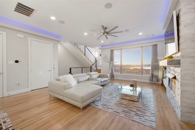 living area featuring visible vents, recessed lighting, stairs, a stone fireplace, and light wood-type flooring