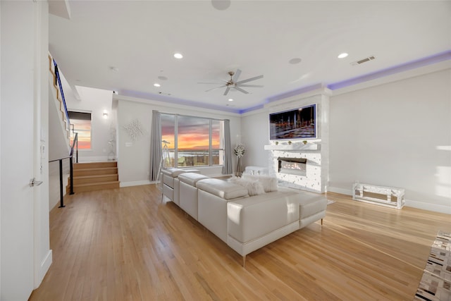 living area with visible vents, light wood-style flooring, recessed lighting, stairs, and a glass covered fireplace