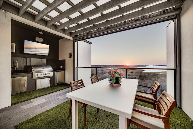 patio terrace at dusk featuring grilling area, a water view, outdoor dining area, and area for grilling