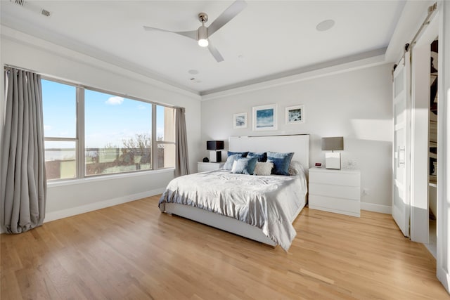 bedroom with visible vents, a barn door, light wood-style floors, and baseboards