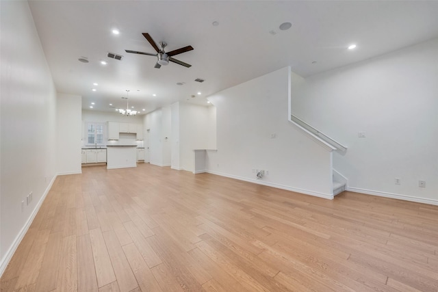 unfurnished living room featuring recessed lighting, ceiling fan with notable chandelier, visible vents, light wood-style floors, and stairs