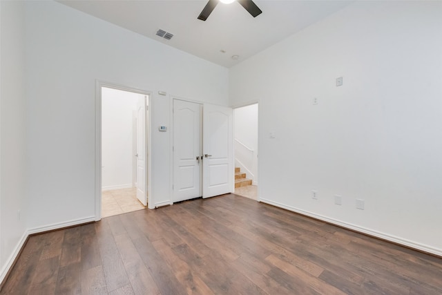 unfurnished bedroom with baseboards, wood finished floors, visible vents, and connected bathroom