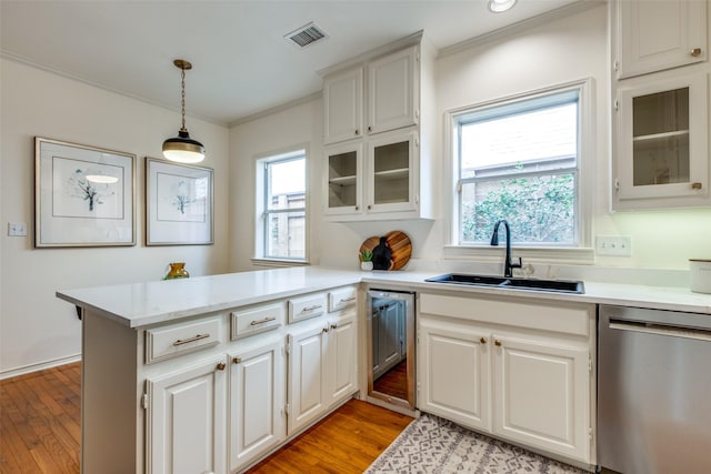 kitchen featuring a peninsula, a sink, visible vents, ornamental molding, and dishwasher