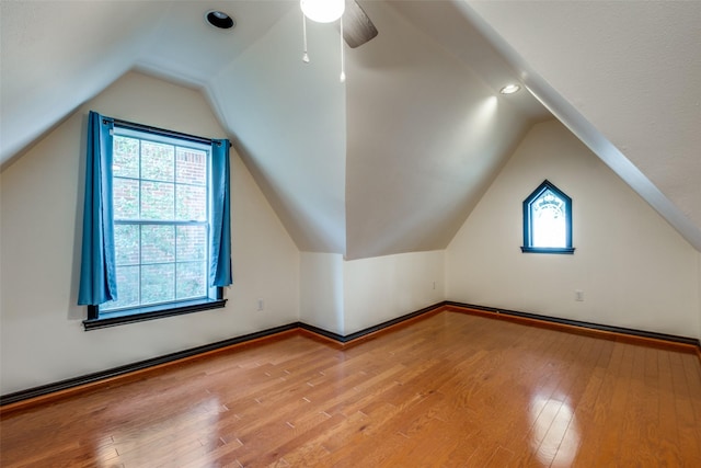 additional living space featuring vaulted ceiling, hardwood / wood-style flooring, and a healthy amount of sunlight