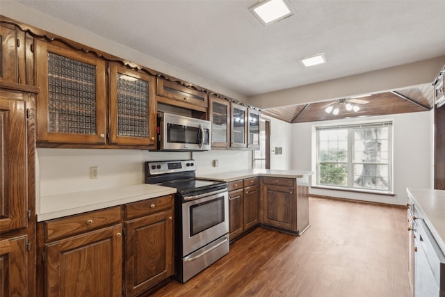 1878 Trail Ridge Dr, Lewisville, TX 75077 - kitchen with stainless steel appliances, dark wood-type flooring, a peninsula, light countertops, and glass insert cabinets