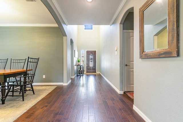 entrance foyer with arched walkways, dark wood-style floors, crown molding, and baseboards