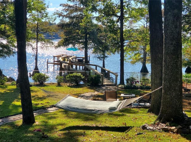 view of dock with a water view and a lawn