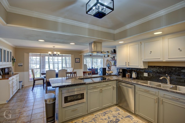 kitchen featuring a peninsula, island exhaust hood, built in microwave, stovetop, and stainless steel dishwasher