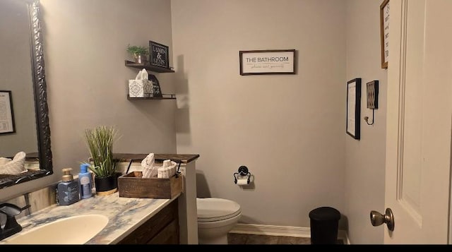 half bathroom with toilet, vanity, and baseboards