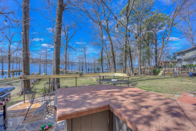 deck featuring a water view, a lawn, and a playground