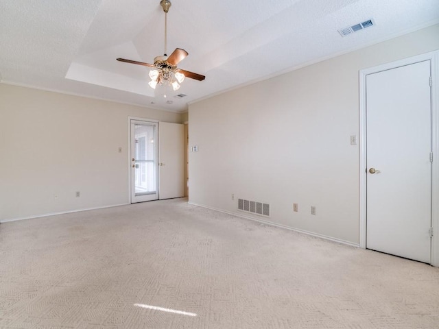 unfurnished room with light carpet, a tray ceiling, visible vents, and a ceiling fan