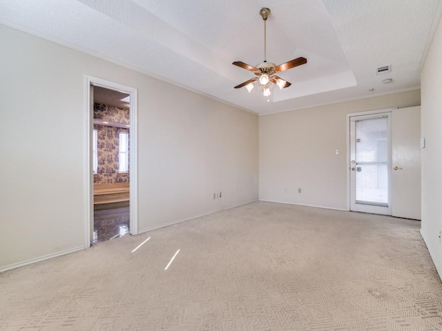 spare room featuring baseboards, a raised ceiling, a ceiling fan, light colored carpet, and a textured ceiling