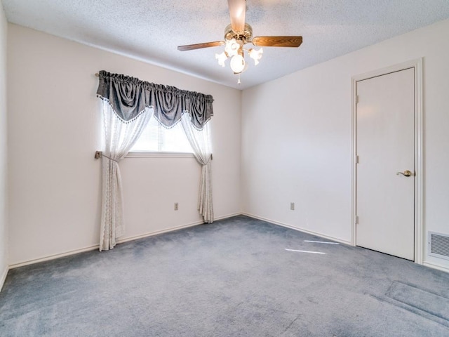 carpeted empty room with ceiling fan, visible vents, and a textured ceiling