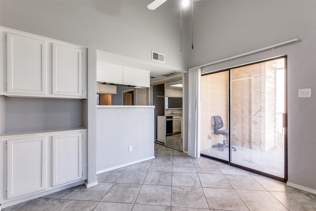 interior space with light tile patterned floors, visible vents, white cabinets, and ceiling fan