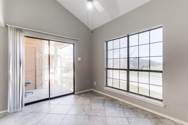 tiled empty room featuring a ceiling fan, baseboards, and vaulted ceiling