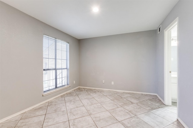 empty room with light tile patterned floors, baseboards, and visible vents