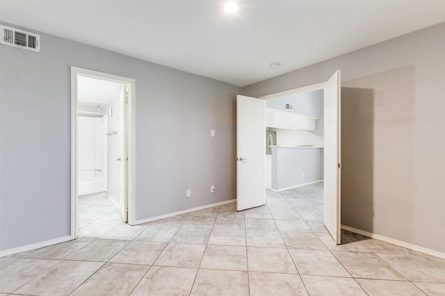 unfurnished bedroom featuring light tile patterned floors, visible vents, baseboards, and connected bathroom