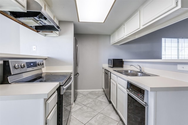 kitchen with a sink, light countertops, appliances with stainless steel finishes, white cabinetry, and wall chimney range hood