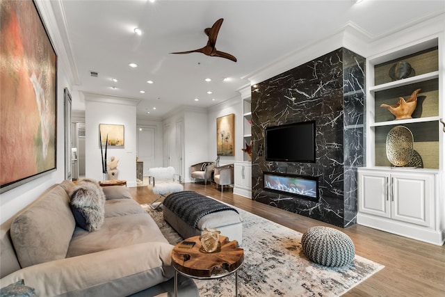 living area featuring a fireplace, crown molding, and wood finished floors