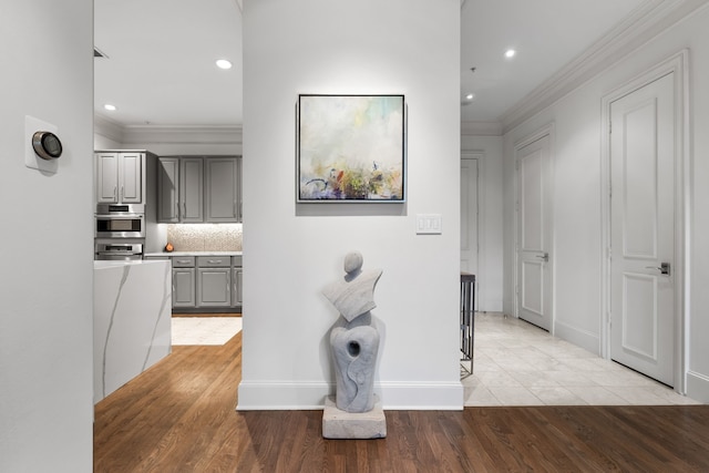 hall with light wood-style flooring, ornamental molding, and recessed lighting