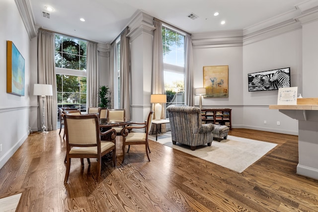 living area featuring ornamental molding, visible vents, and wood finished floors