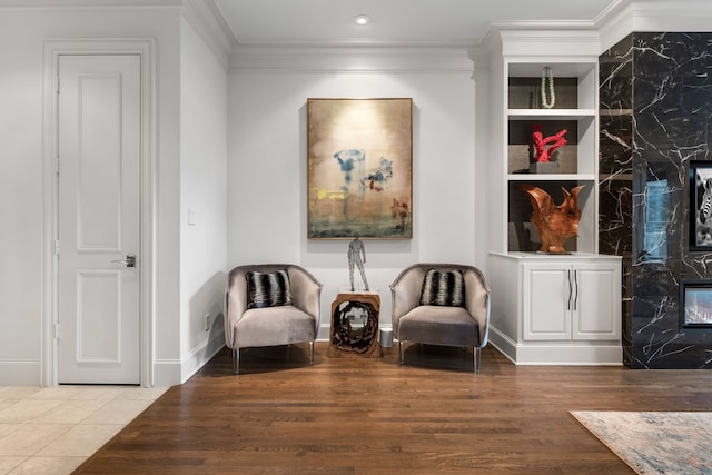 sitting room with recessed lighting, a fireplace, wood finished floors, baseboards, and crown molding