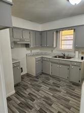 kitchen featuring light countertops, dark wood-type flooring, a sink, and gray cabinetry