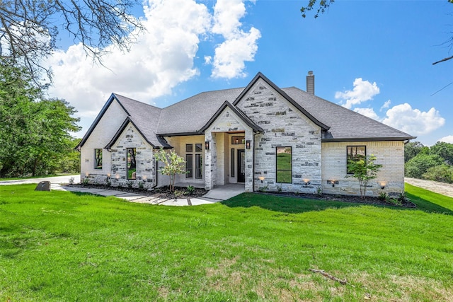 view of front of property featuring a front lawn, a chimney, a shingled roof, and brick siding