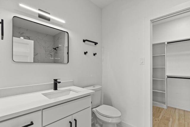 full bathroom with toilet, wood finished floors, a spacious closet, walk in shower, and vanity