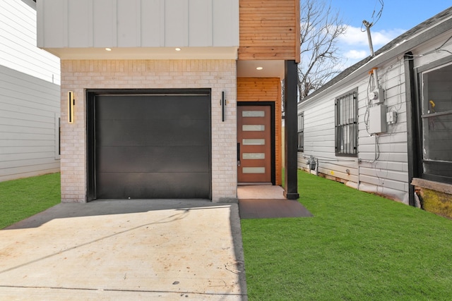 doorway to property with a garage, a yard, brick siding, and driveway