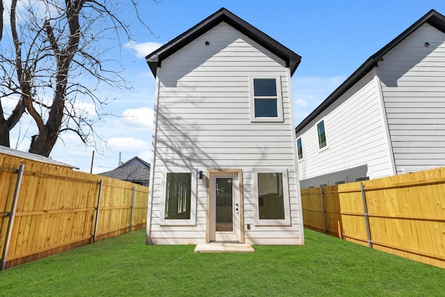 rear view of property with a fenced backyard and a yard