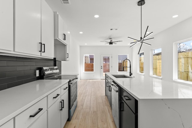 kitchen featuring a sink, visible vents, light wood-style floors, appliances with stainless steel finishes, and tasteful backsplash